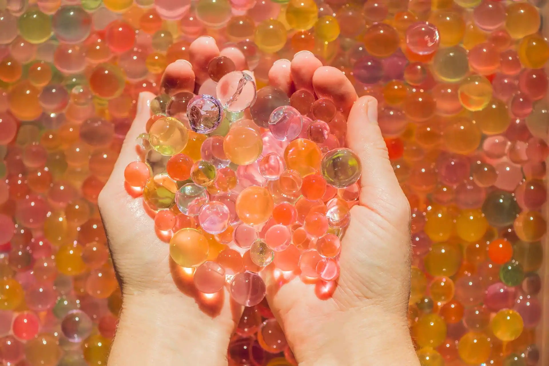 Hands holding colorful water beads.