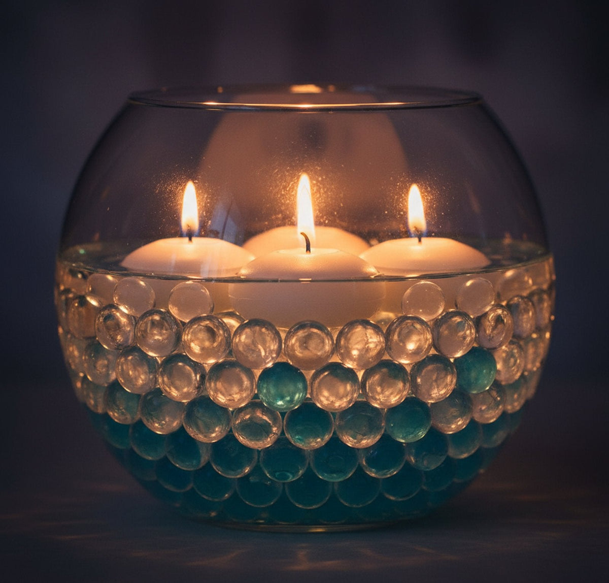 Floating candles over clear water beads in a glass bowl