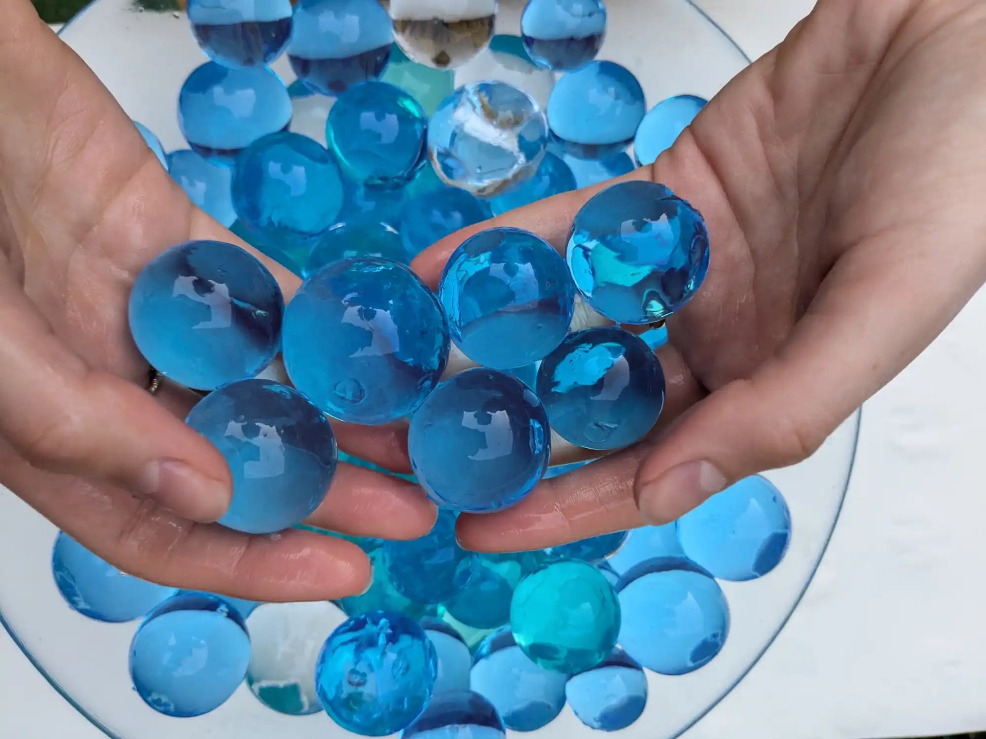 Hands holding blue water beads.